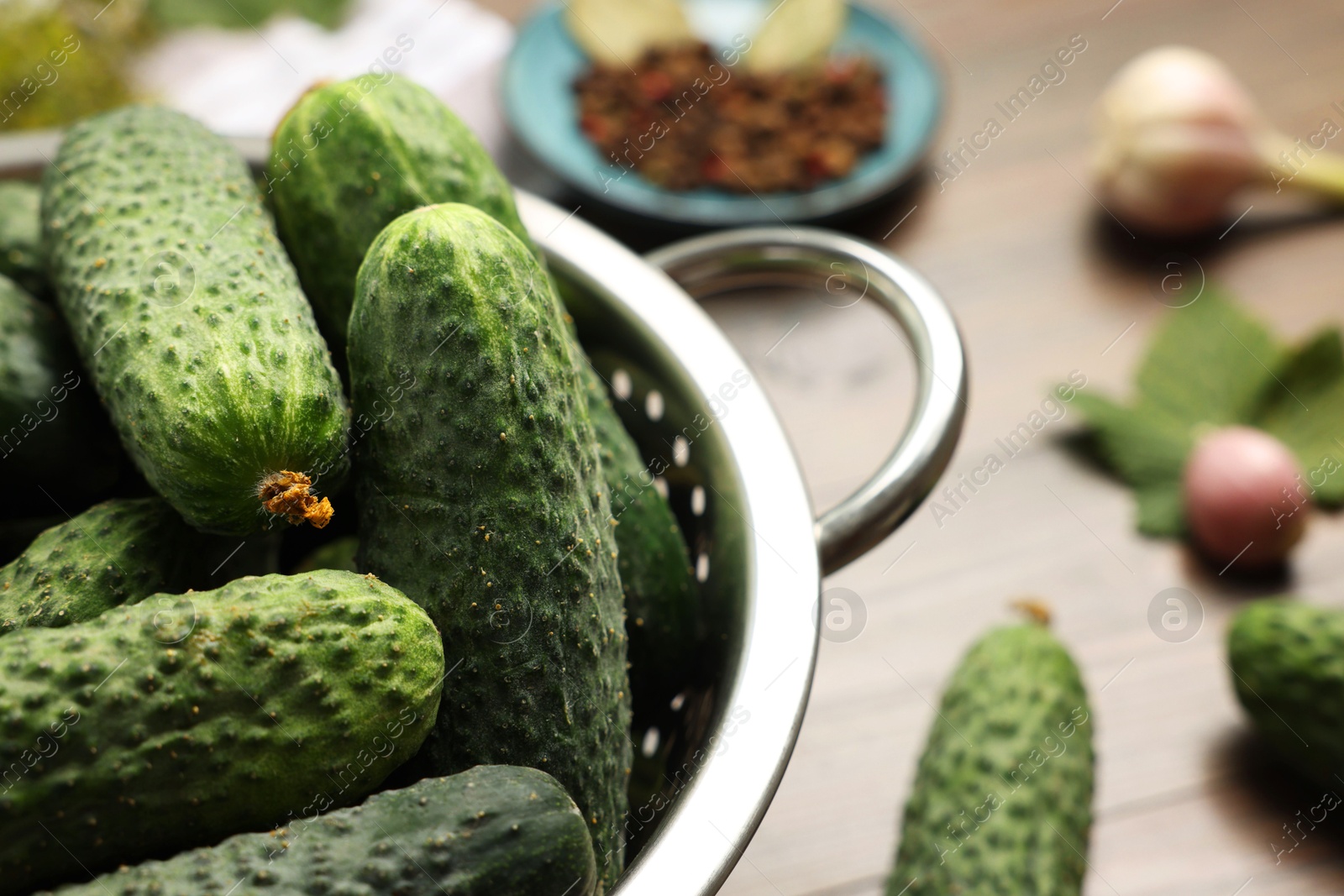 Photo of Fresh green cucumbers in colander on table, closeup