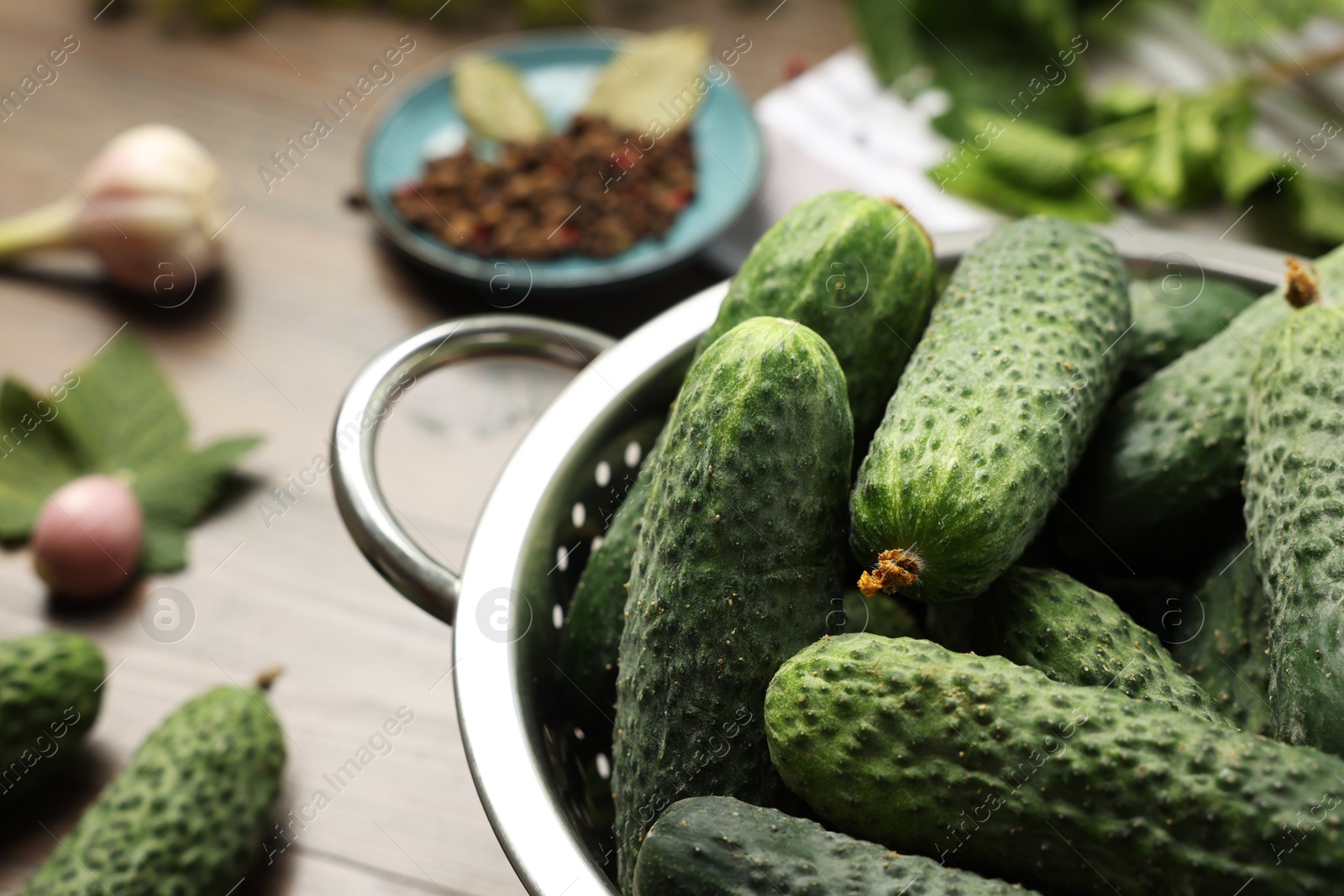 Photo of Fresh green cucumbers in colander on table, closeup