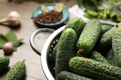 Photo of Fresh green cucumbers in colander on table, closeup