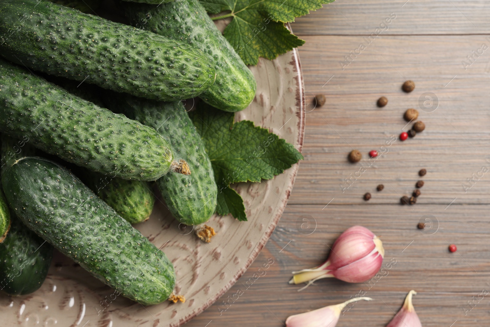 Photo of Fresh green cucumbers and spices on wooden table, flat lay