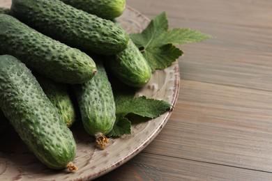 Fresh green cucumbers on wooden table, space for text