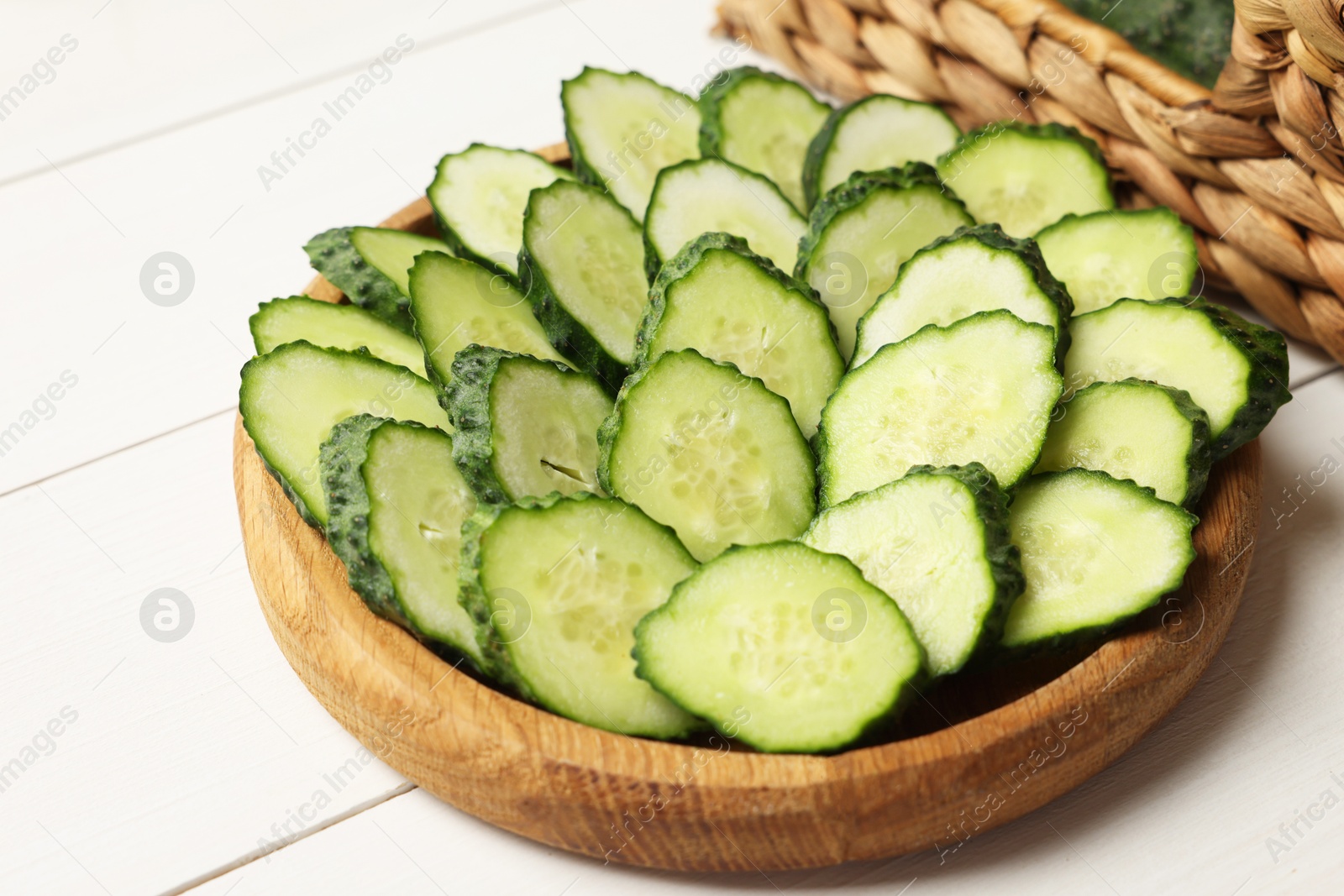 Photo of Slices of fresh cucumbers on white wooden table