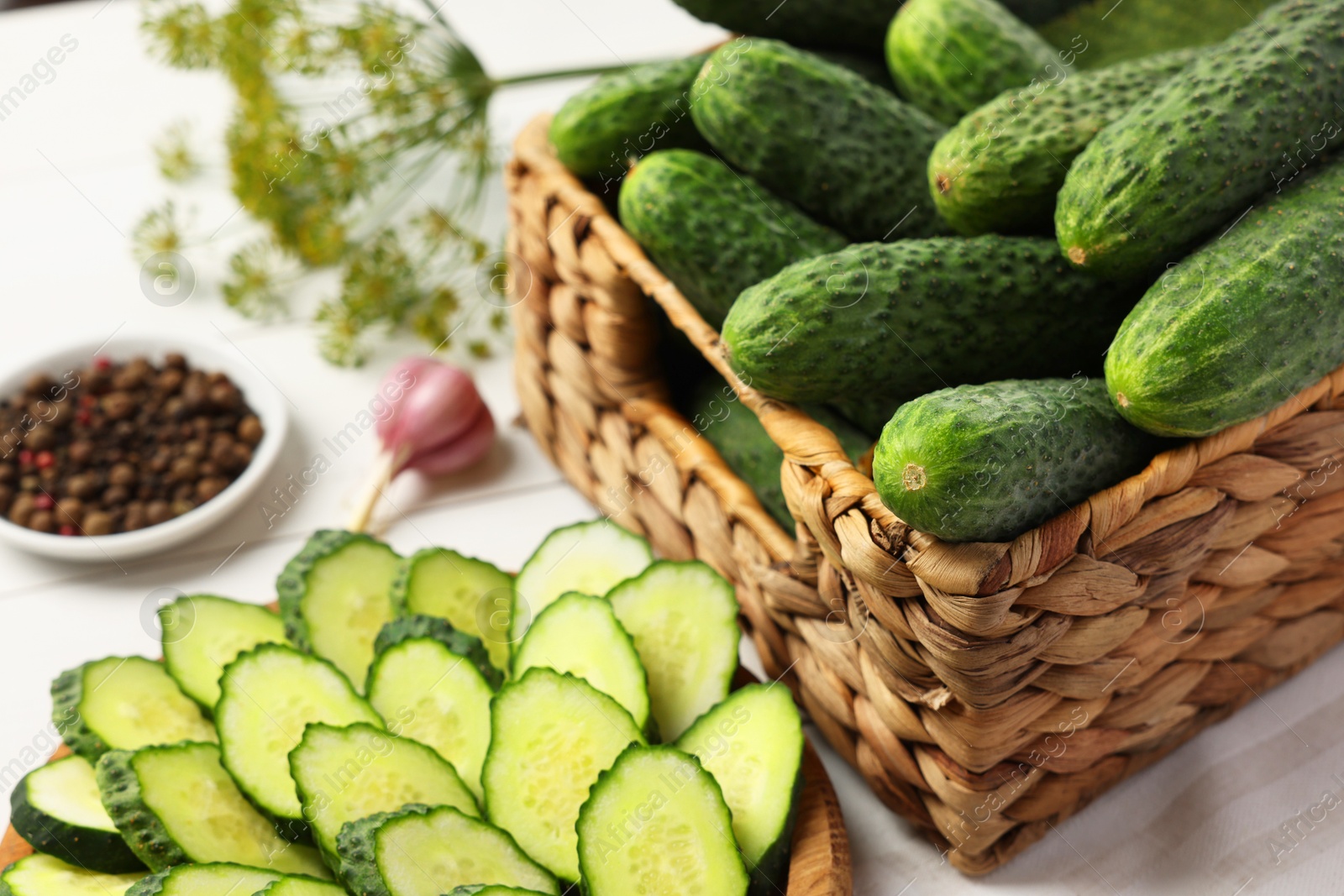 Photo of Fresh whole and cut cucumbers on white table, closeup