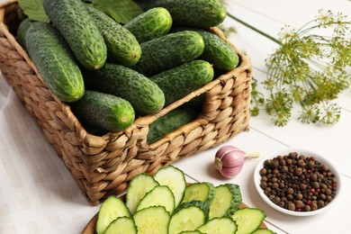 Photo of Fresh green cucumbers and spices on white wooden table, closeup