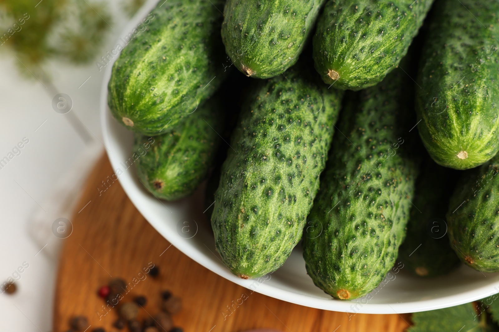 Photo of Fresh green cucumbers in bowl on white table, closeup