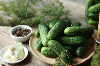 Photo of Fresh cucumbers and spices on wooden table, closeup. Preparation for pickling