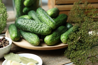 Photo of Fresh cucumbers, dill and spices on wooden table, closeup. Preparation for pickling