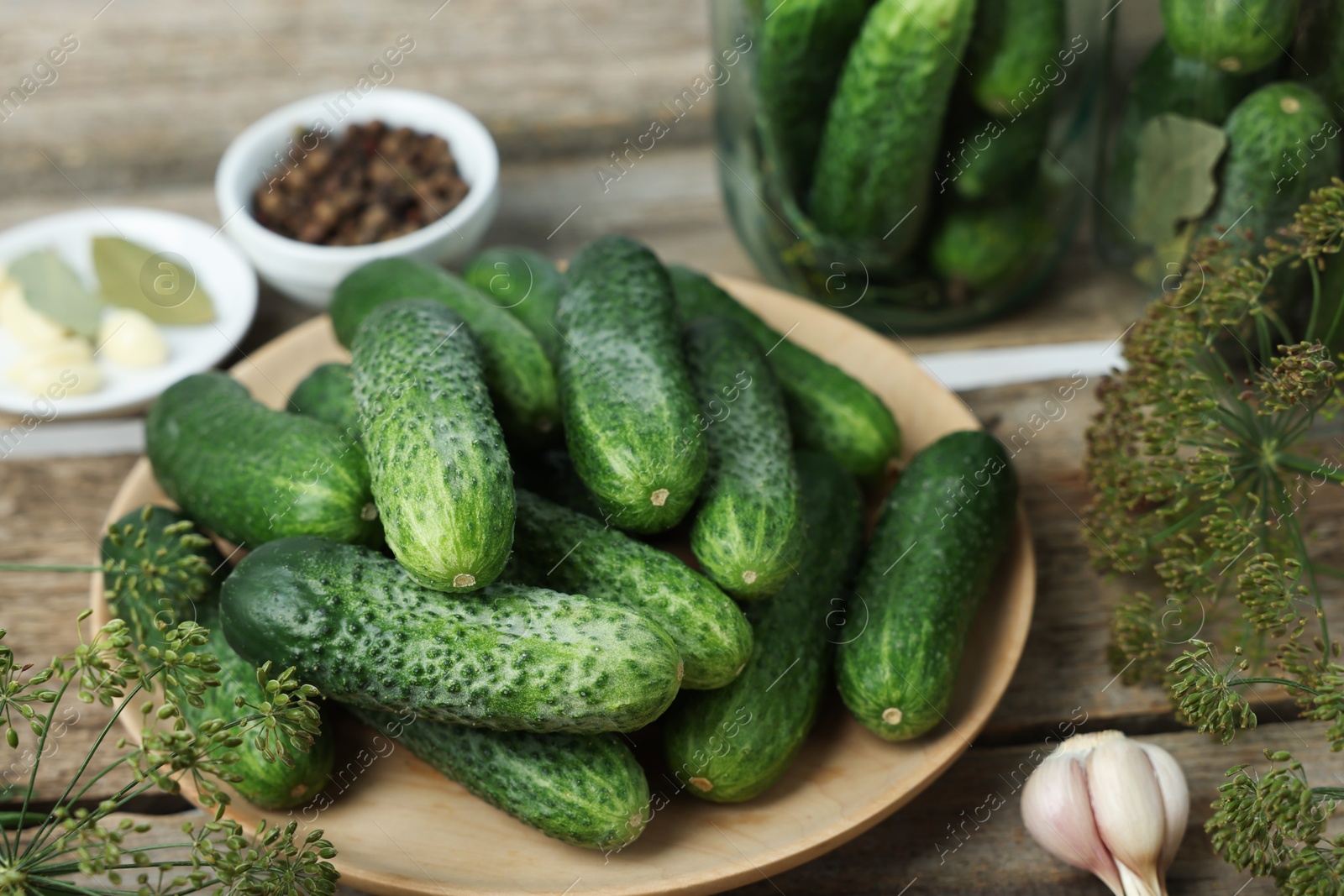 Photo of Fresh cucumbers, dill and spices on wooden table, closeup. Preparation for pickling