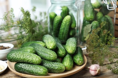 Photo of Fresh cucumbers, dill and garlic on wooden table, closeup. Preparation for pickling