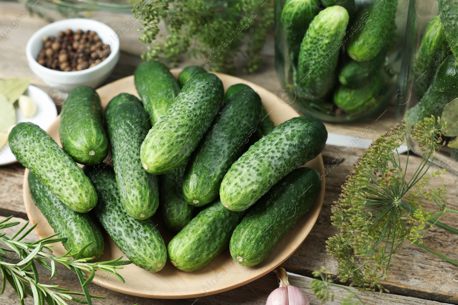 Photo of Fresh cucumbers, dill and spices on wooden table, closeup. Preparation for pickling