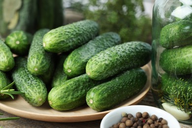 Fresh cucumbers and peppercorns on wooden table, closeup. Preparation for pickling