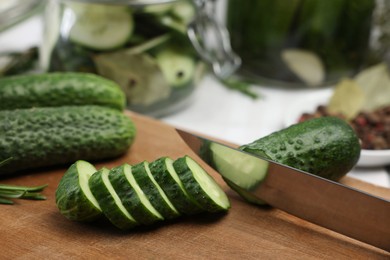 Photo of Cutting fresh ripe cucumber at table, closeup