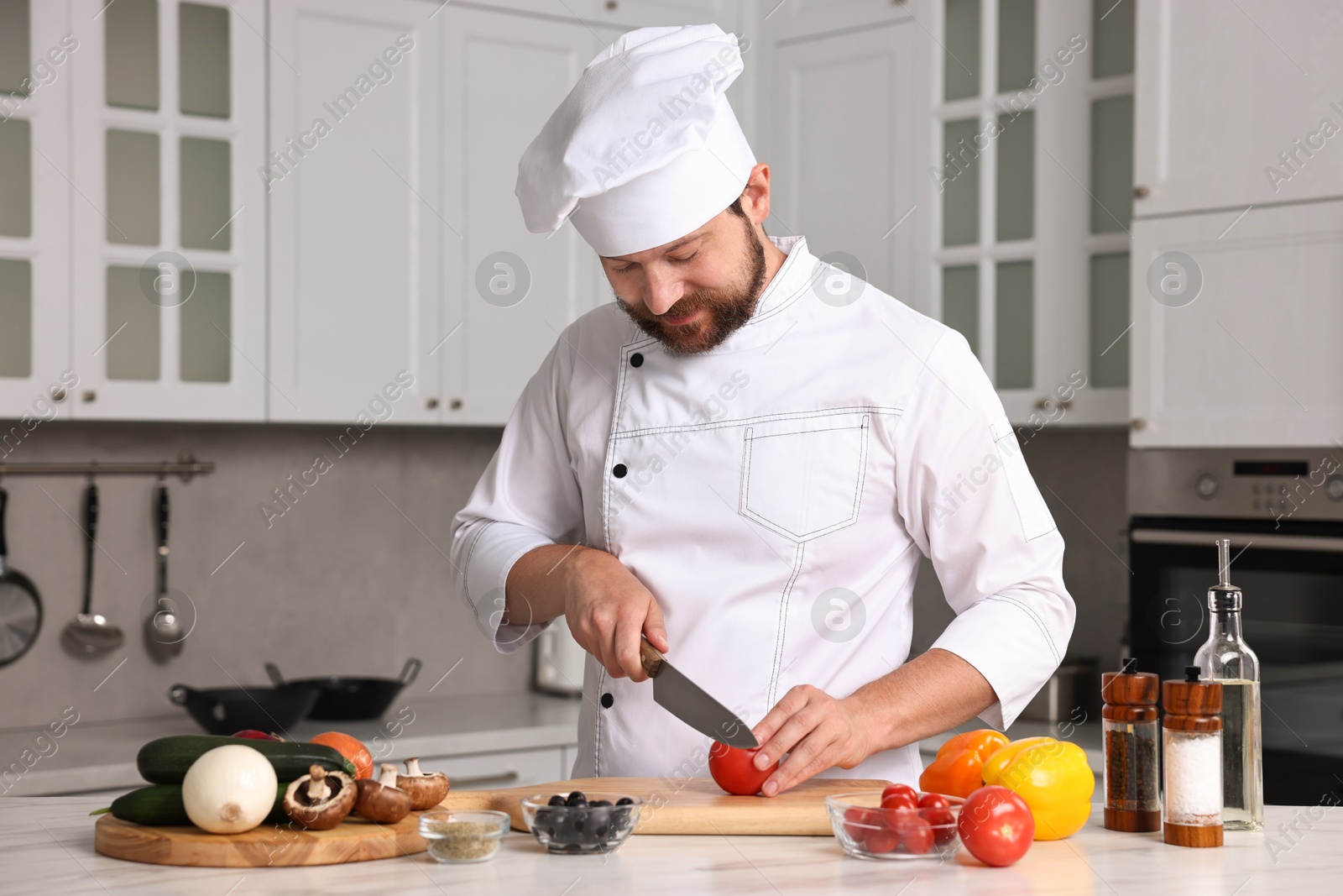 Photo of Professional chef cutting tomato at table in kitchen