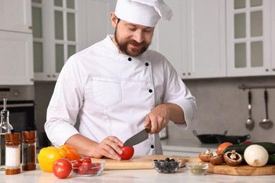 Photo of Professional chef cutting tomato at table in kitchen