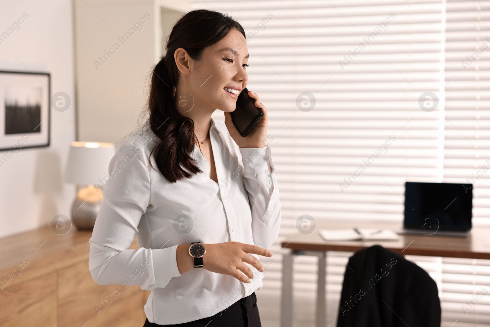 Photo of Smiling businesswoman talking on smartphone in office. Space for text