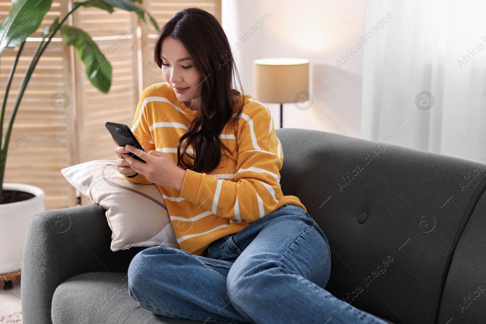 Photo of Beautiful woman with smartphone on sofa at home