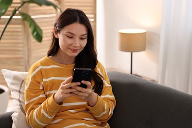 Photo of Beautiful young woman using smartphone at home