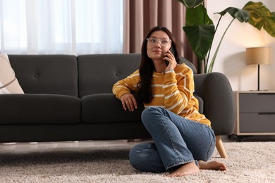 Beautiful woman talking on smartphone at home