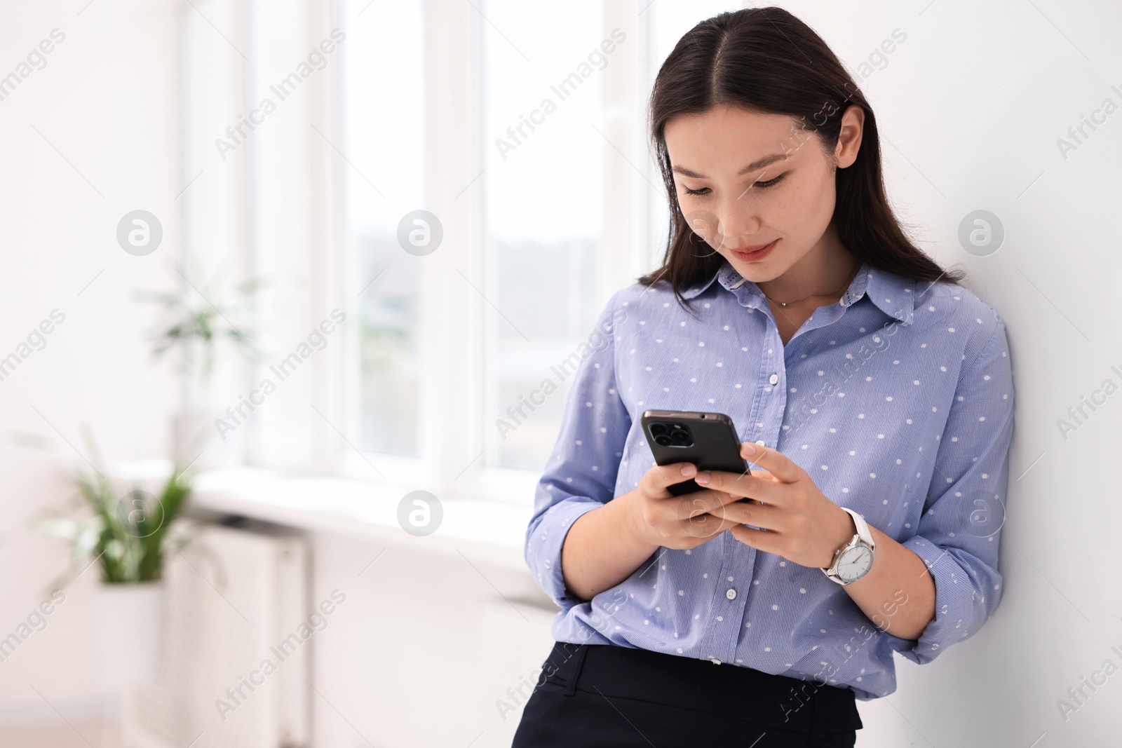 Photo of Beautiful businesswoman with smartphone in office. Space for text