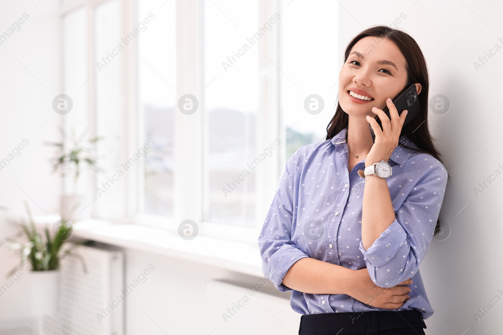 Photo of Smiling businesswoman talking on smartphone in office. Space for text