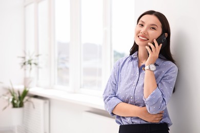 Photo of Smiling businesswoman talking on smartphone in office. Space for text