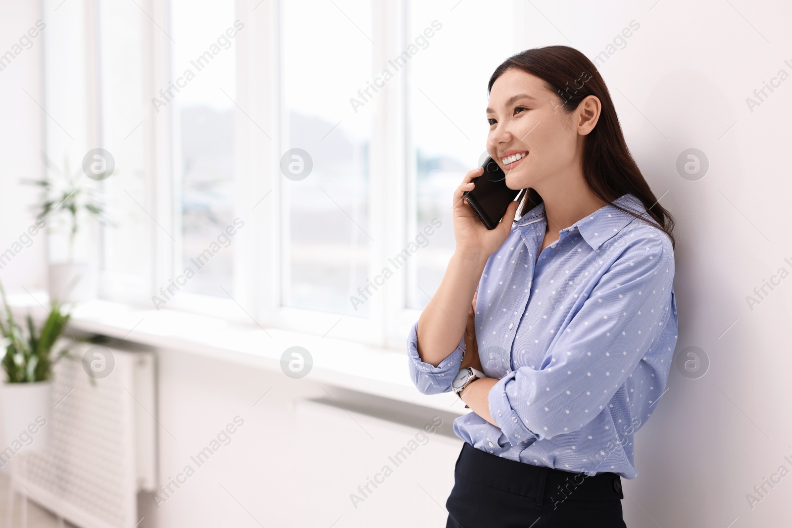 Photo of Smiling businesswoman talking on smartphone in office. Space for text