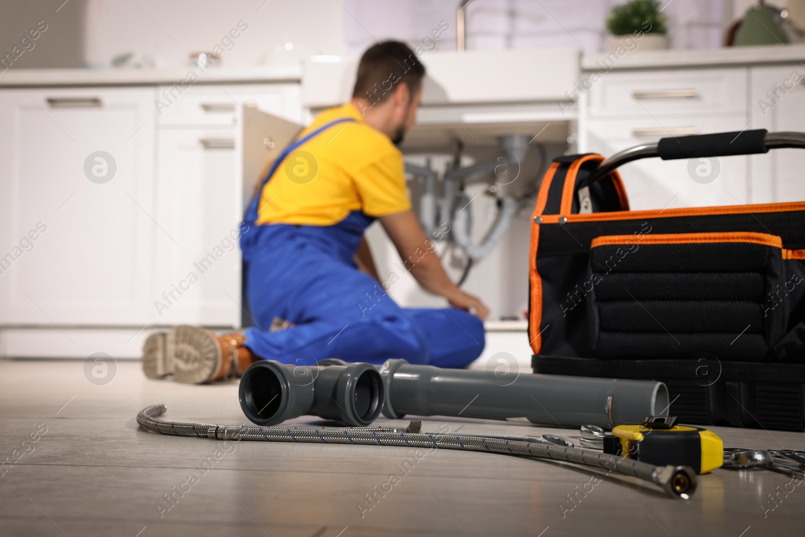 Photo of Professional plumber fixing piping system at home, focus on tools