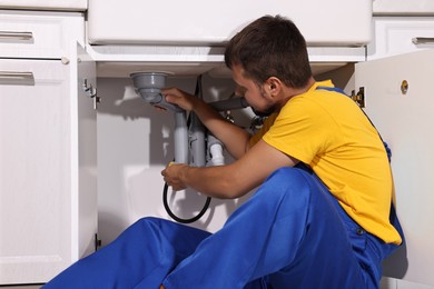 Photo of Professional plumber fixing piping system at home