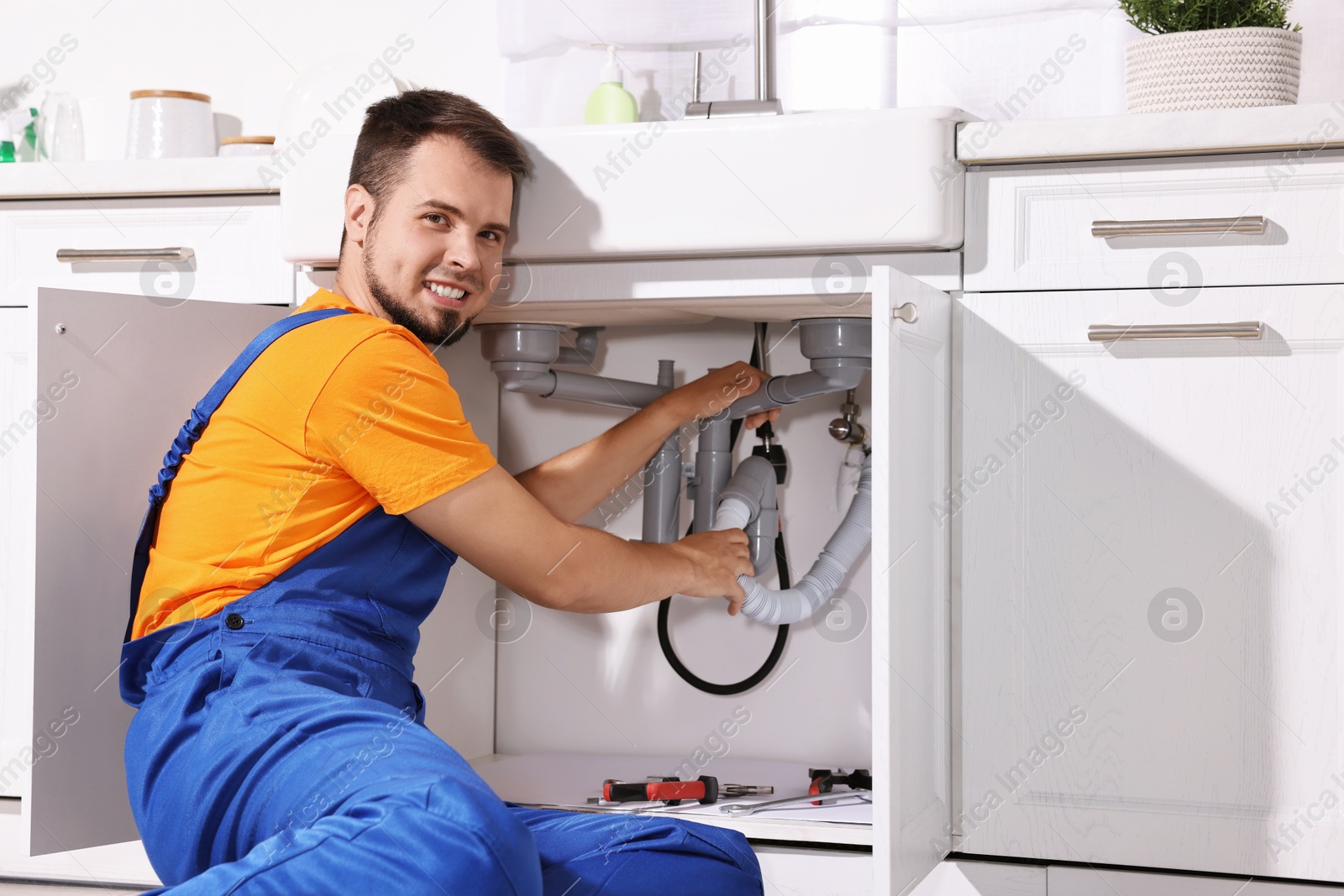 Photo of Professional plumber fixing piping system at home