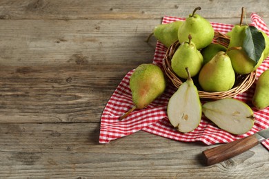 Photo of Fresh green pears, wicker basket and napkin on wooden table. Space for text