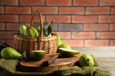 Photo of Fresh green pears and knife on wooden table against brick wall. Space for text