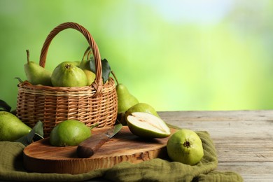 Photo of Fresh pears, knife and napkin on wooden table against blurred green background. Space for text