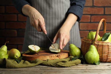 Photo of Woman cutting fresh green pears at wooden table, closeup