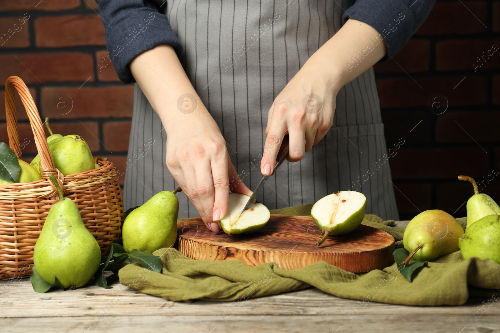 Photo of Woman cutting fresh green pears at wooden table, closeup