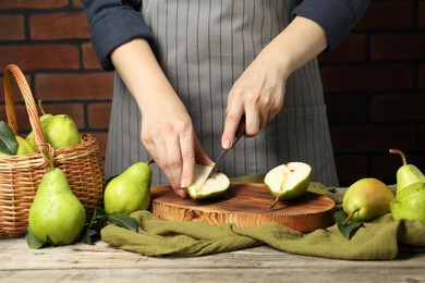 Photo of Woman cutting fresh green pears at wooden table, closeup