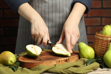 Photo of Woman cutting fresh green pears at wooden table, closeup