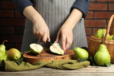 Photo of Woman cutting fresh green pears at wooden table, closeup