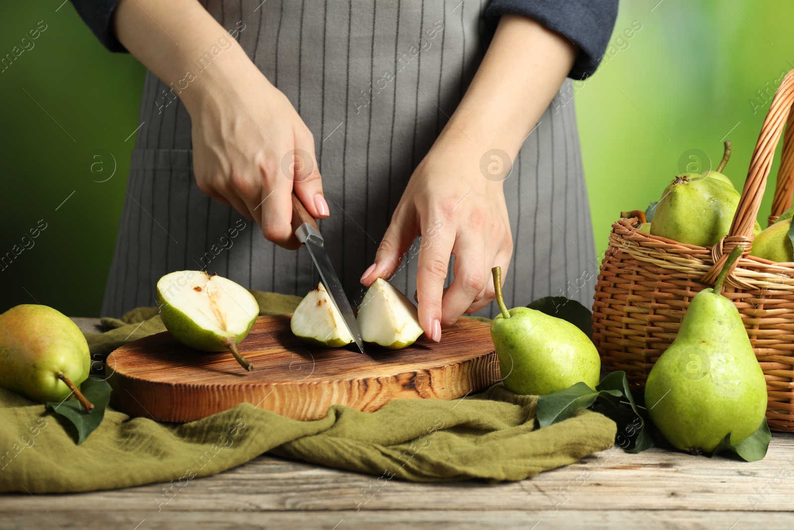 Photo of Woman cutting fresh green pears at wooden table, closeup