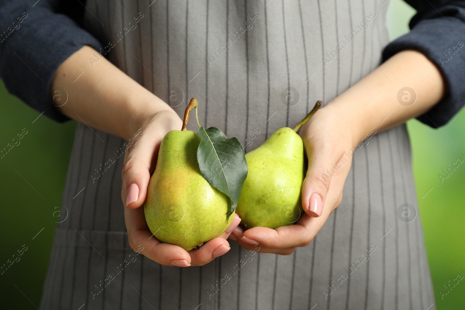 Photo of Woman with fresh pears on green background, closeup