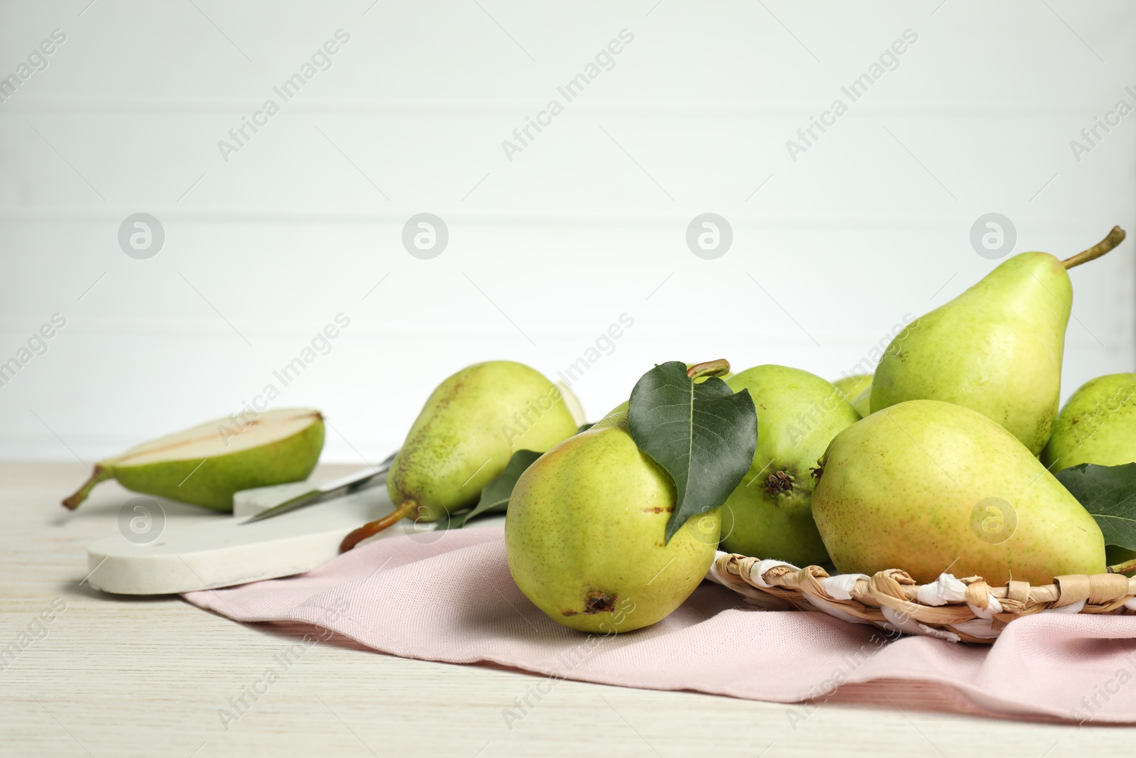 Photo of Fresh green pears with leaves on light wooden table. Space for text