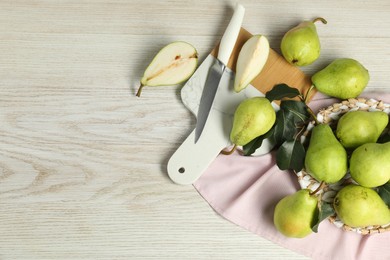 Photo of Fresh green pears with leaves and knife on light wooden table. Space for text