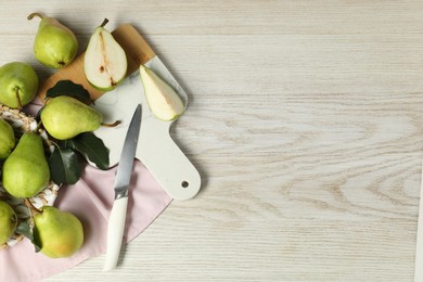 Photo of Fresh green pears with leaves and knife on light wooden table. Space for text