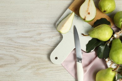 Photo of Fresh green pears with leaves and knife on light wooden table. Space for text