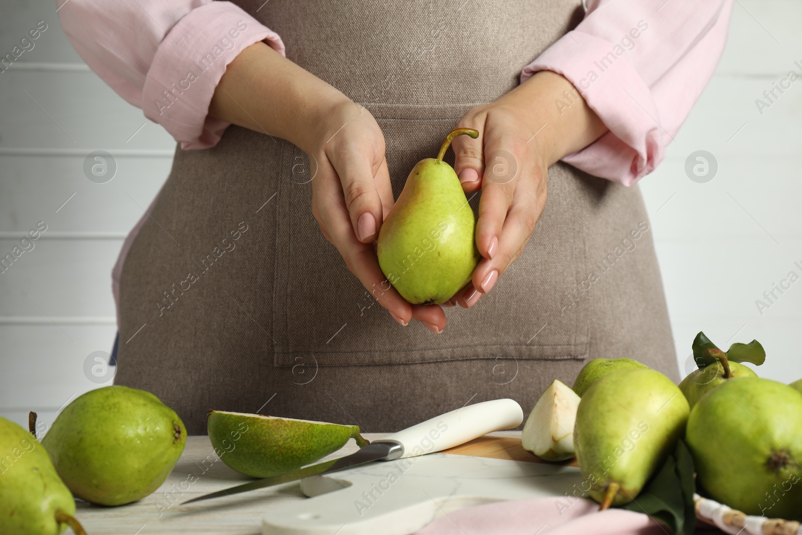 Photo of Woman with fresh green pears at light wooden table, closeup