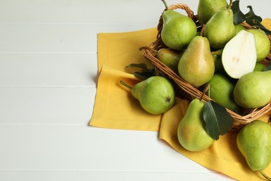 Photo of Fresh green pears with leaves and basket on white table, above view. Space for text