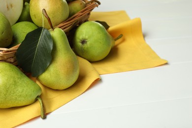 Photo of Fresh green pears and basket on white table, closeup