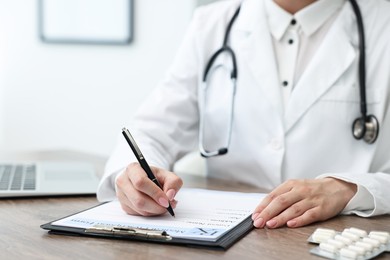 Photo of Doctor writing prescription at wooden table in clinic, closeup