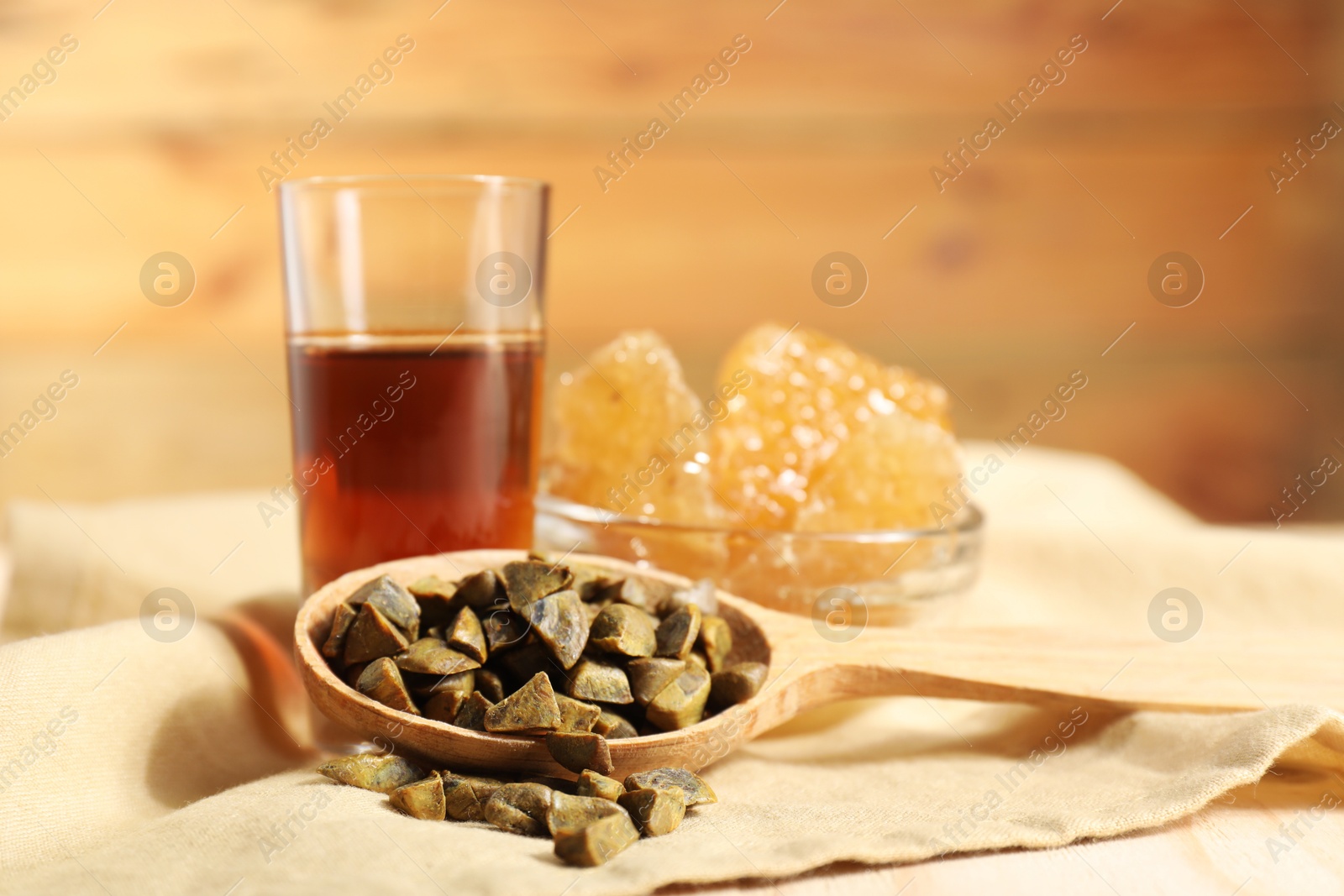 Photo of Spoon with propolis granules, honey tincture and honeycombs on table, closeup. Alternative medicine