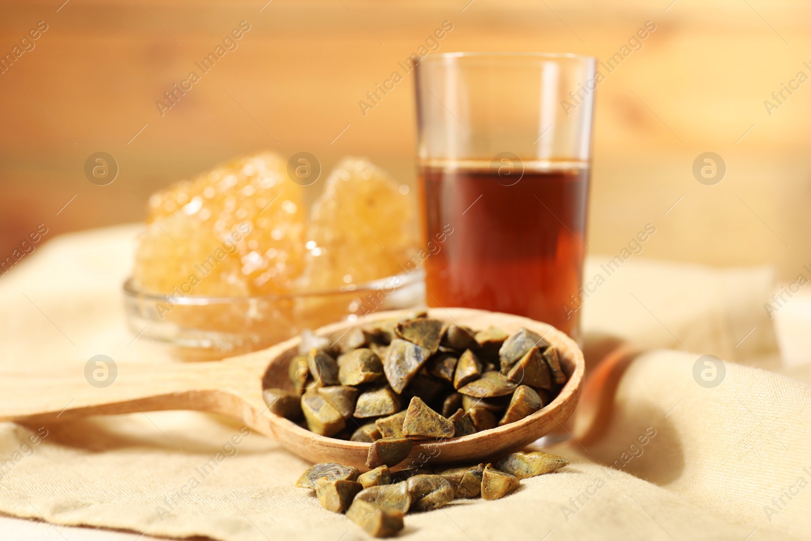 Photo of Spoon with propolis granules, honey tincture and honeycombs on table, closeup. Alternative medicine