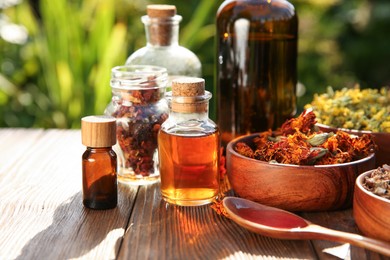 Photo of Different tinctures and ingredients on wooden table outdoors